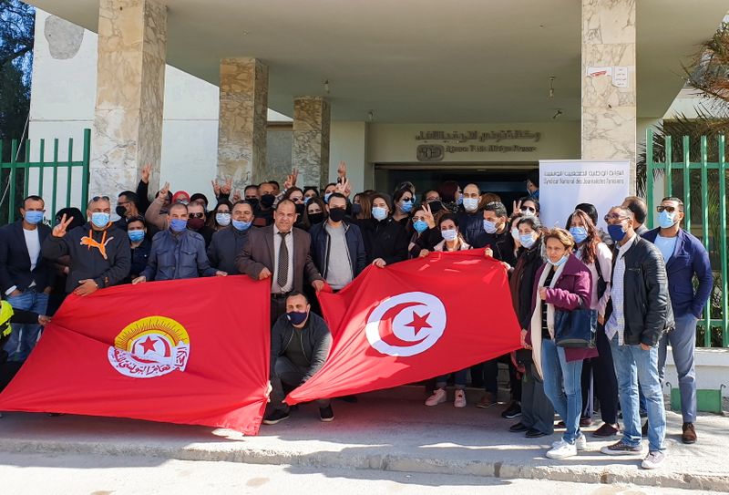Journalists in Tunisia’s state news agency carry flags as they