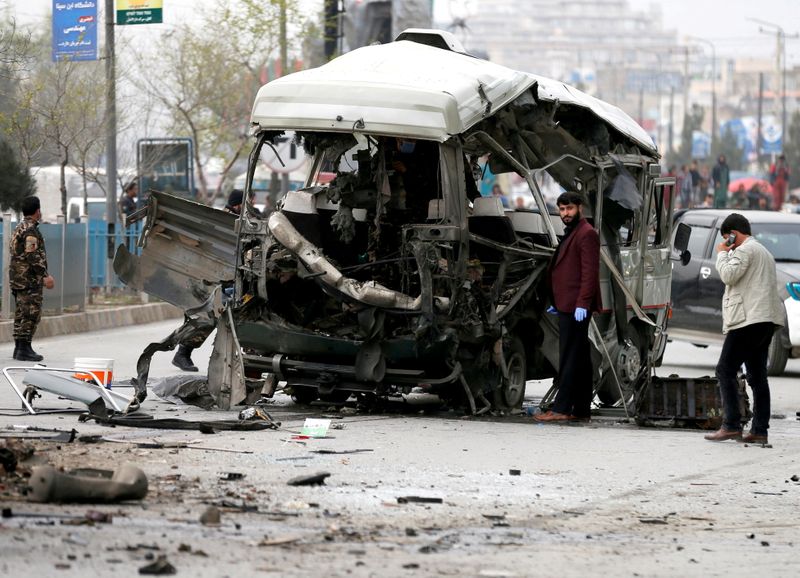 FILE PHOTO: Afghan officials inspect a damaged minibus after a