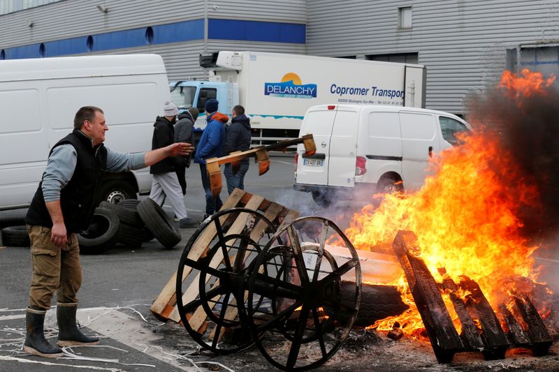FILE PHOTO: A fisherman puts a tyre onto a fire