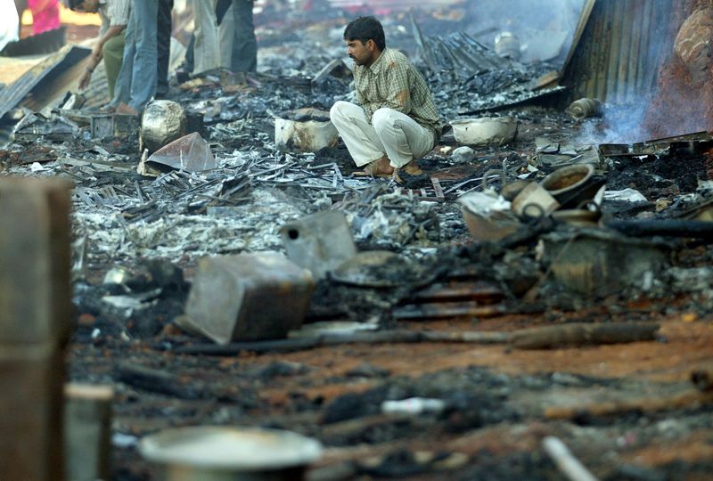 FILE PHOTO: A survivor sits among the debris of burnt