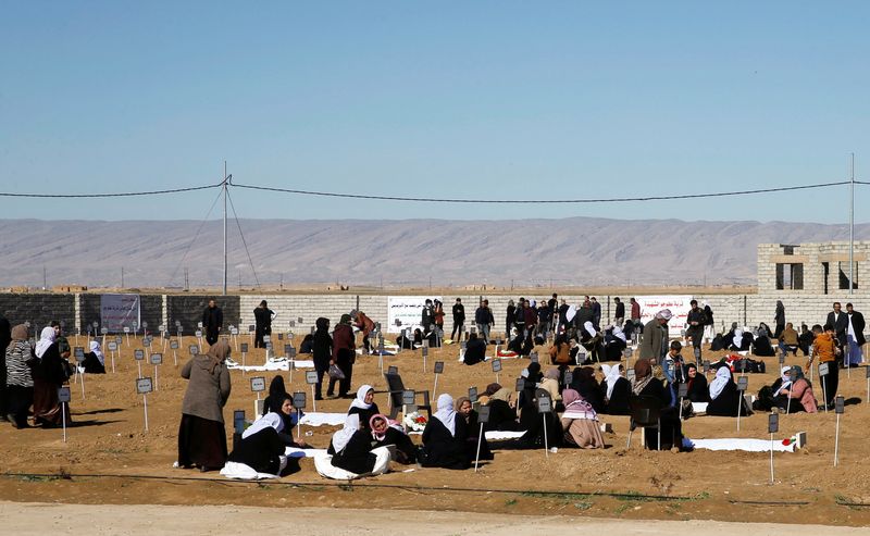 Yazidi minority residents visit a cemetery for victims killed in