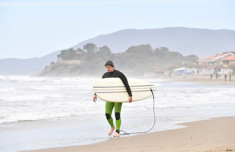 FILE PHOTO: A surfer walks on the beach as coronavirus