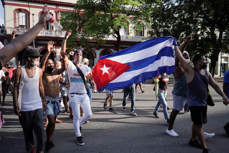People hold Cuba’s national flag during protests against and in