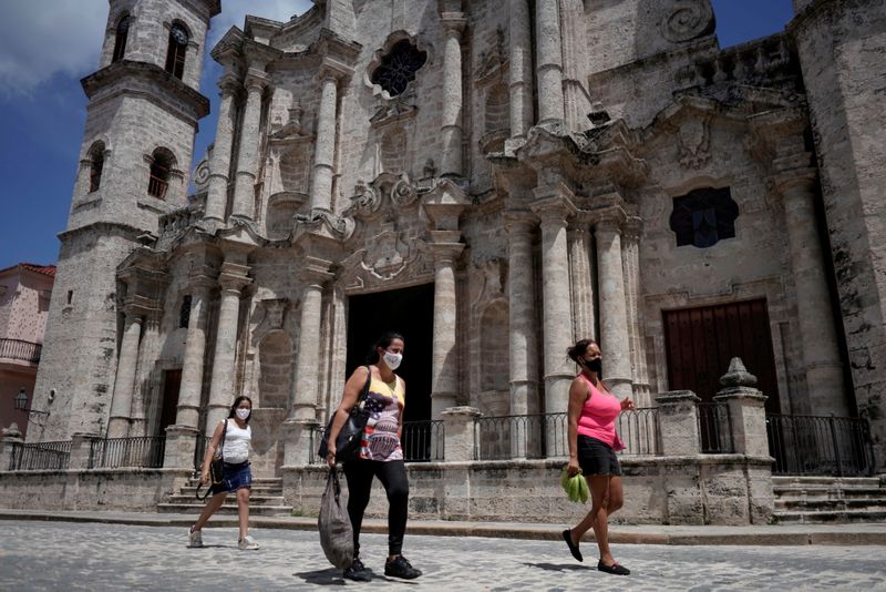 People pass by in front of the Havana’s Cathedral