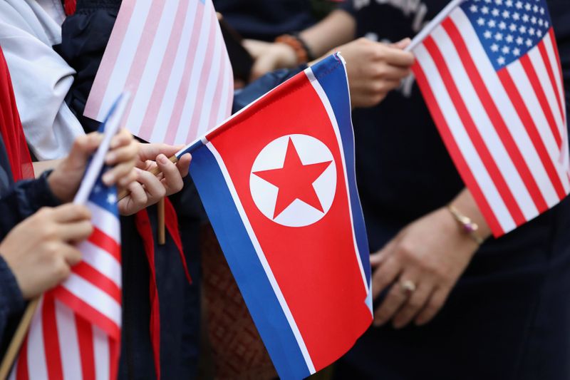 Bystanders holding North Korea and U.S. flags wait for the