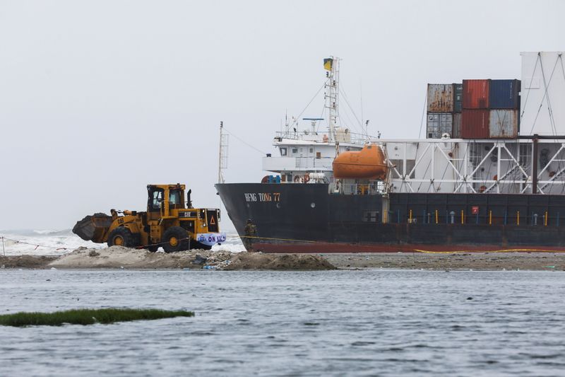 A wheel loader clears the ground near stranded cargo ship