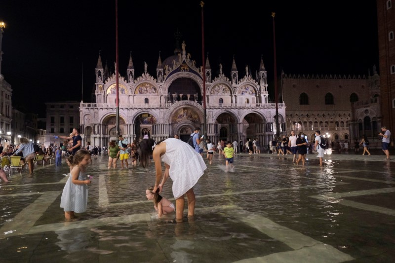 People walk in a flooded St. Mark’s Square during an