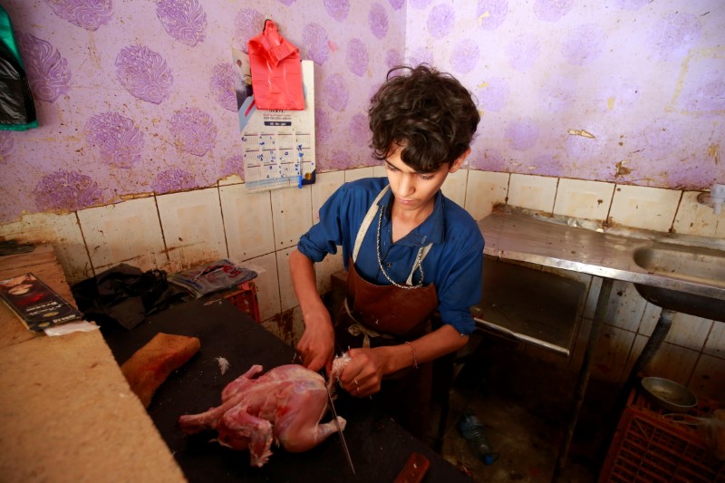 Harith Mansour cuts a chicken at a butchery in Sanaa