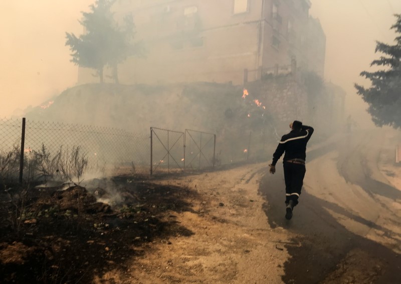 A civil protection rescue worker walks near smoke rising from