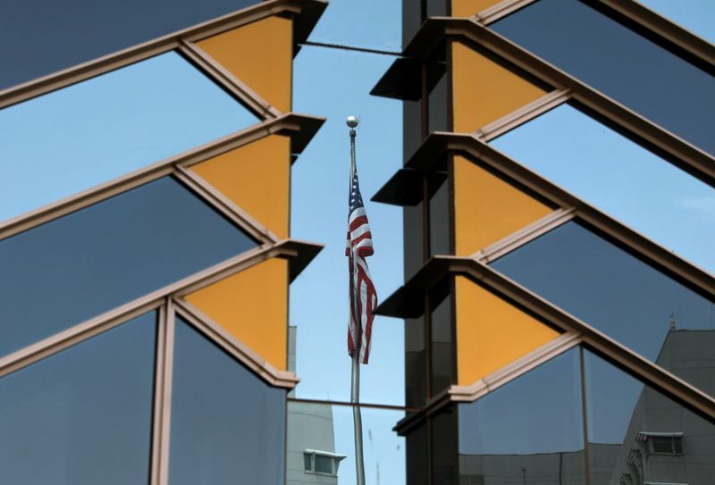 The U.S. flag is reflected on the windows of the