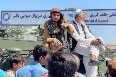A member of Taliban forces (L) sits on a an