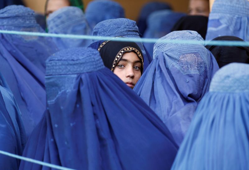 A girl looks on among Afghan women lining up to
