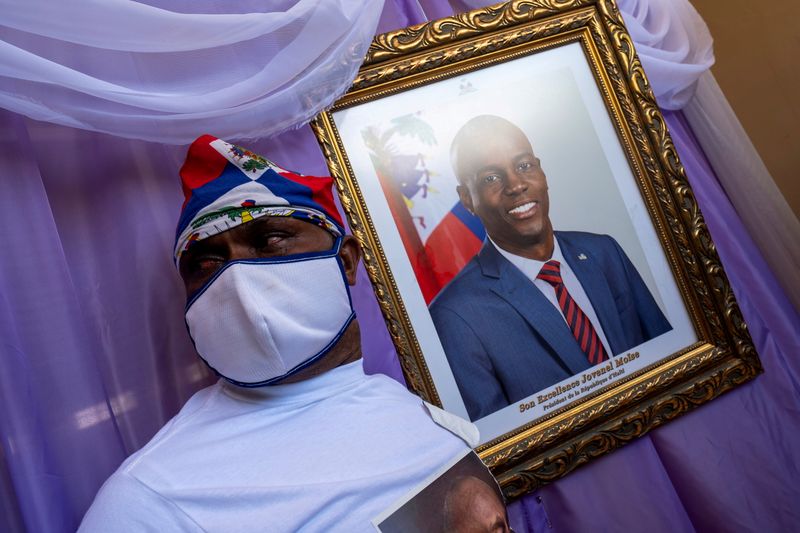 FILE PHOTO: A man stands next to a portrait of