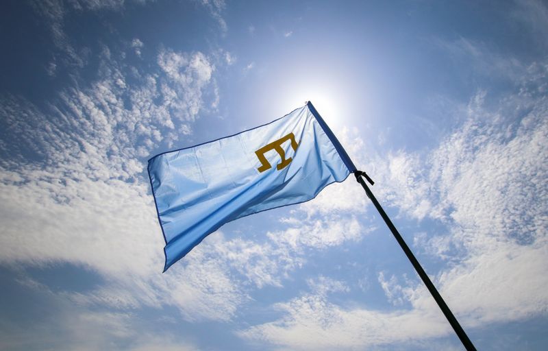 A Crimean Tatars flag flies at a rally, commemorating Crimean