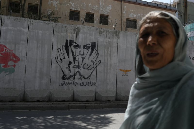 A mural reading “gender equality” is seen behind a woman
