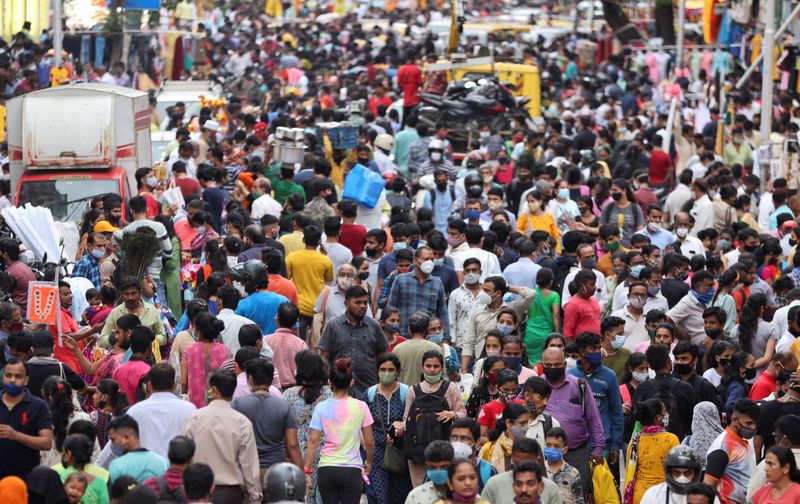 People walk in a crowded market amidst the spread of