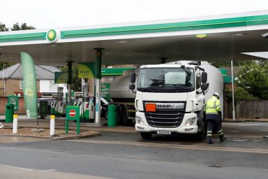 A driver walks past his tanker after completing a fuel