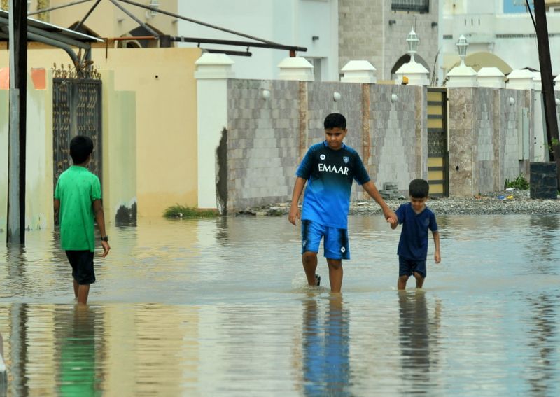Locals walk in flooded streets caused by Cyclone Shaheen in