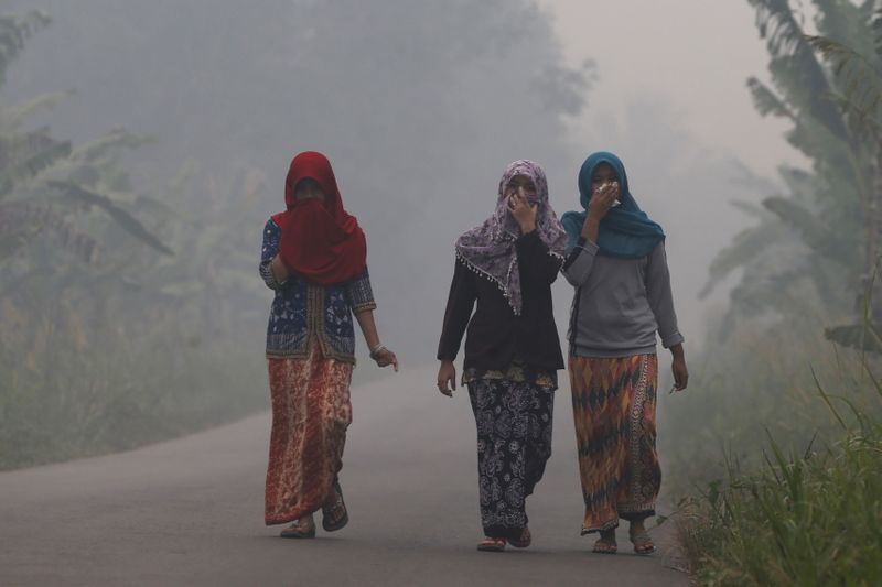 FILE PHOTO: Villagers walk on a street as the haze
