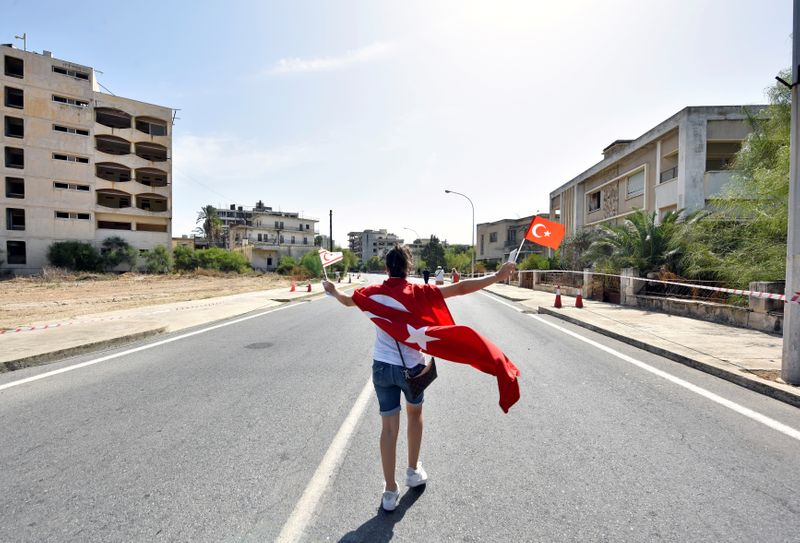 A woman walks while holding Turkish and Turkish Cypriot flags