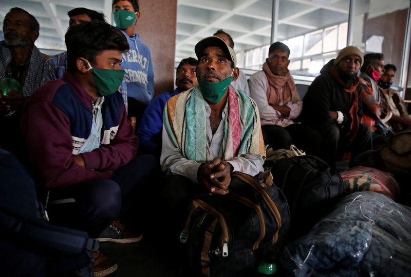 Indian migrant workers wait inside a railway station to board