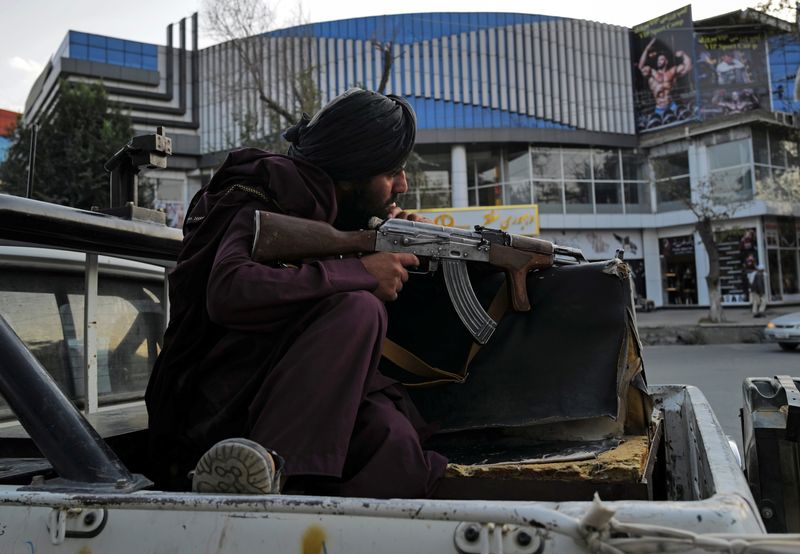 A Taliban fighter sits guard on a vehicle  while