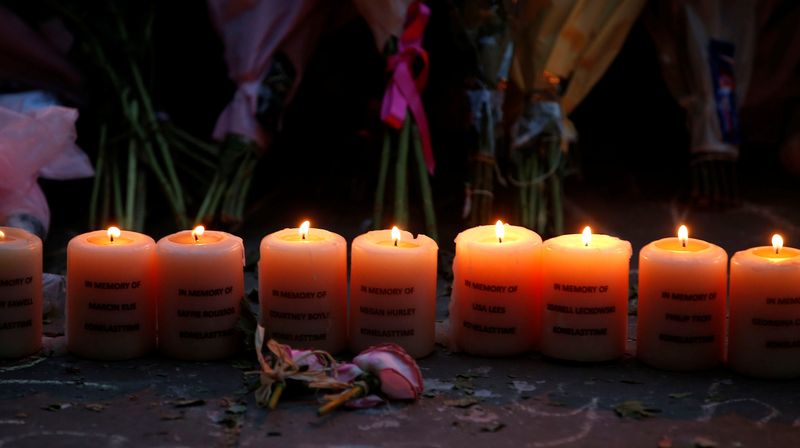 Candles burn with the names of the dead during the