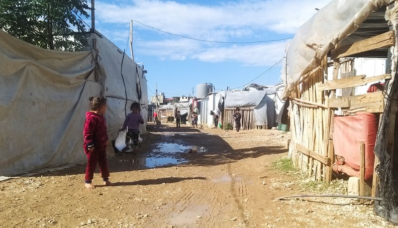 Syrian refugee children walk near tents at an informal tented