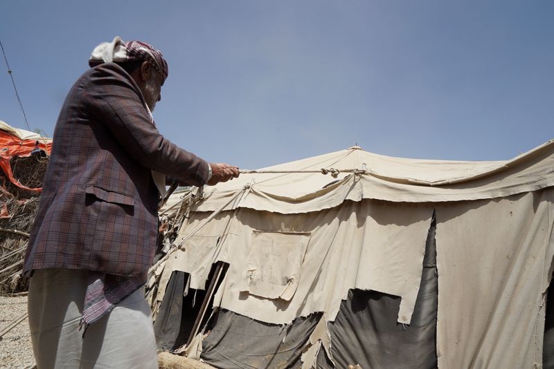 Man stabilizes a tent at a camp for internally displaced