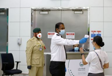 FILE PHOTO: A security man takes temperature of a woman
