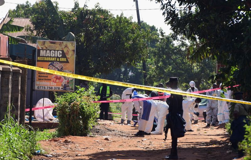 Ugandan police members and explosives experts secure the scene of