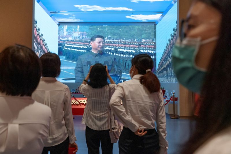 People look at a screen showing Chinese President Xi Jinping