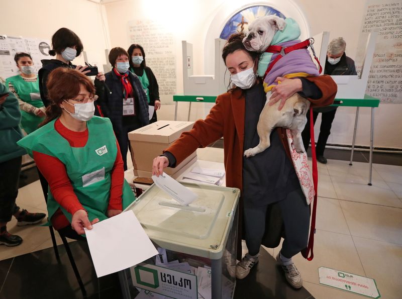 A woman holds her dog as she casts a ballot
