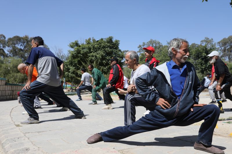 People stretch out as they perform fitness exercises at a