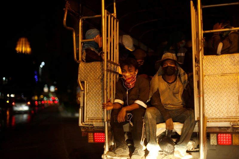 Migrant construction workers are transported in a truck amid the