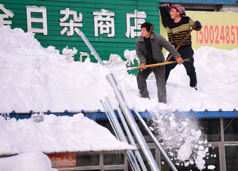 Men clear snow from a roof following heavy snowfall in