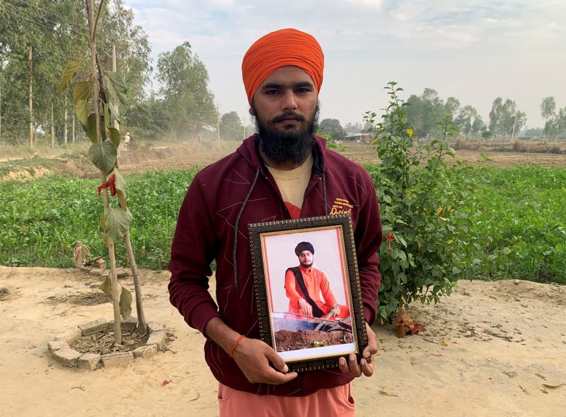 Guru Sevak Singh poses with a photograph of his brother
