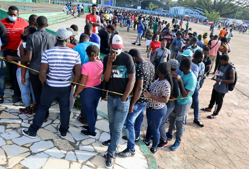 FILE PHOTO: Migrants wait in line for asylum processing by