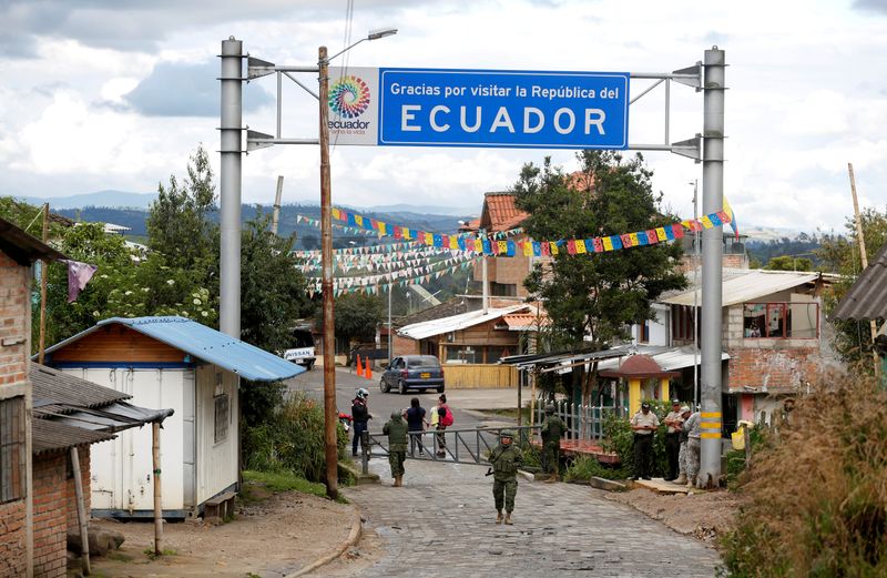 Soldiers stand guard on the Ecuadoran side of a border