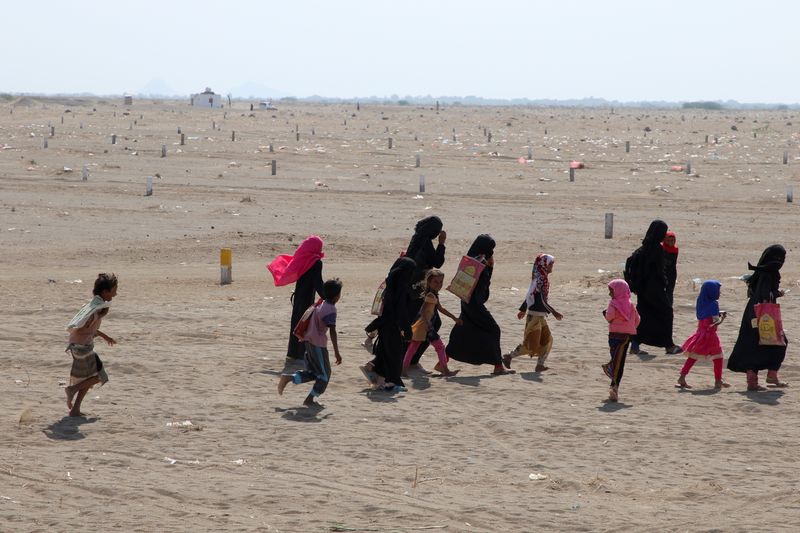 Women and children walk near al-Wara camp for internally displaced