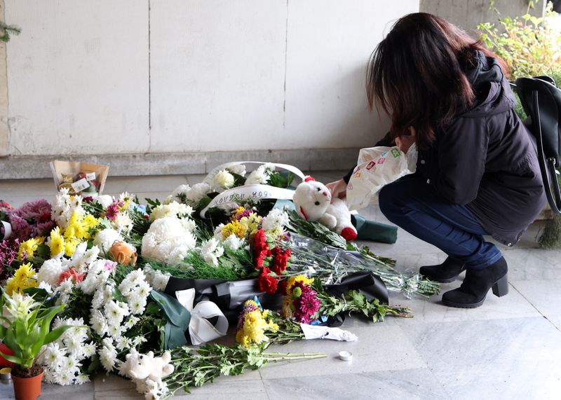 Woman places a teddy bear at a makeshift memorial for