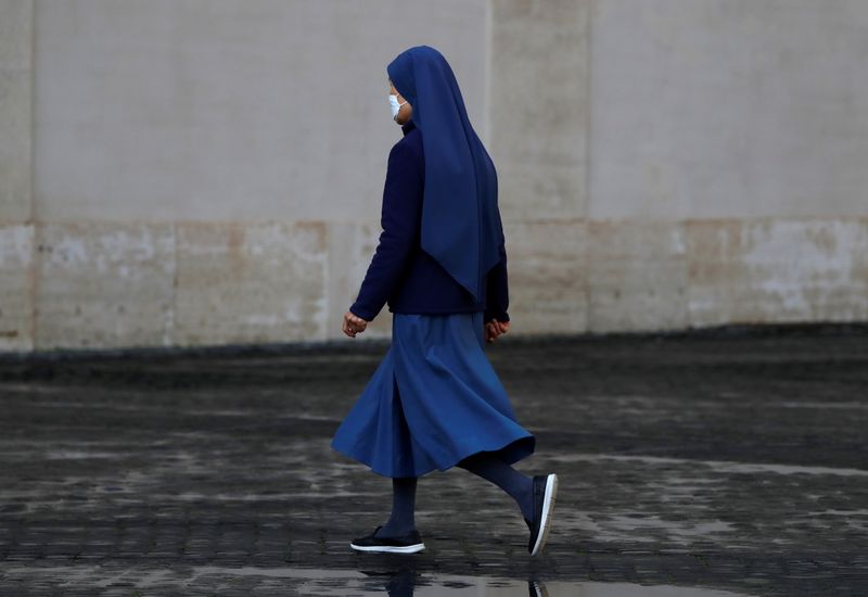 A nun walks in the San Damaso Courtyard at the
