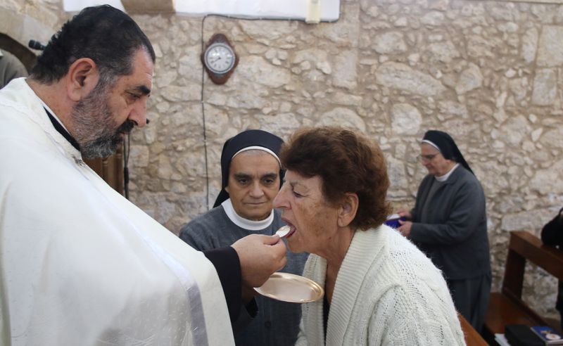 Father Iosif Skender, a Maronite priest, gives Holy Communion to