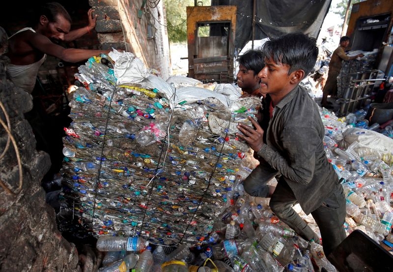 FILE PHOTO: Workers push a bundle of crushed plastic bottles