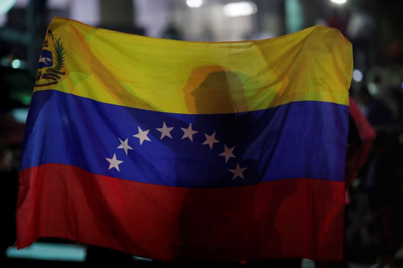 A woman holds a Venezuelan flag while participating in a