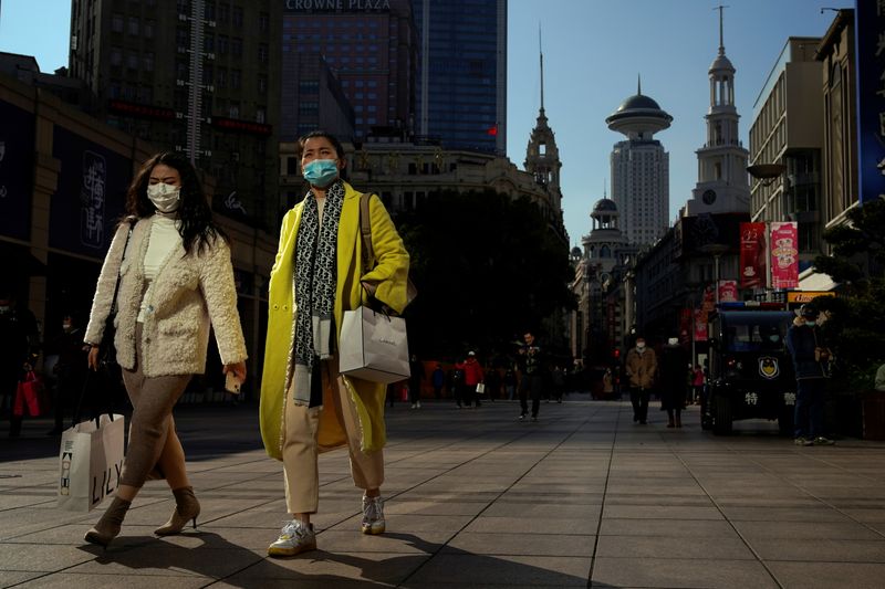 People wearing protective masks walk on a street, following the