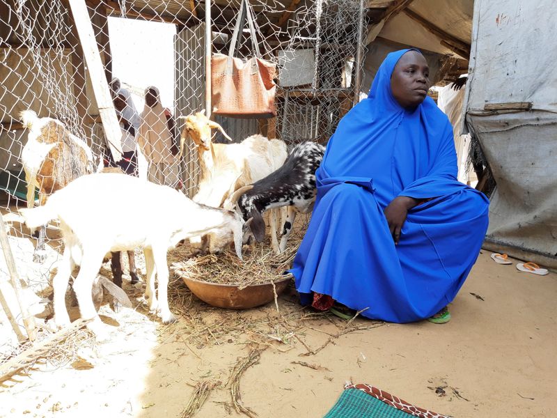 Hauwa Kukuda sits next to her goats during interview with