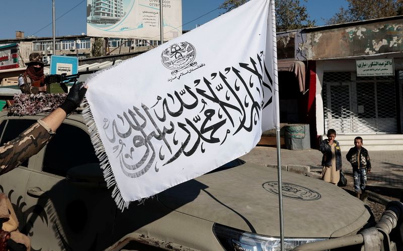 Taliban fighter displays their flag at a checkpoint in Kabul