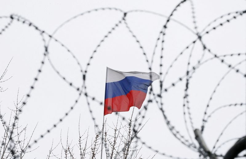 The Russian flag is seen through barbed wire as it