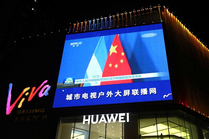 A screen shows news footage of flags of the People’s